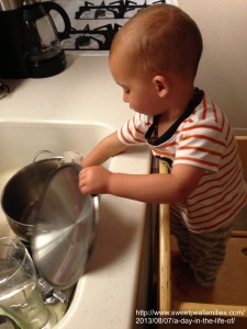 using the learning tower to help wash some dishes 